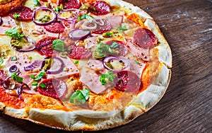 Pizza with Mozzarella cheese, ham, tomato sauce, salami, onion, pepper, Spices and Fresh basil. Italian pizza on wooden table