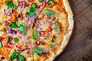 Pizza with Mozzarella cheese, onion, tuna fish, tomato sauce, pepper, basil. Italian pizza on wooden table