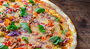 Pizza with Mozzarella cheese, onion, tuna fish, tomato sauce, pepper, basil. Italian pizza on wooden table