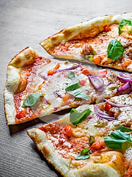 Pizza with Mozzarella cheese, onion, tuna fish, tomato sauce, pepper, basil. Italian pizza on wooden table