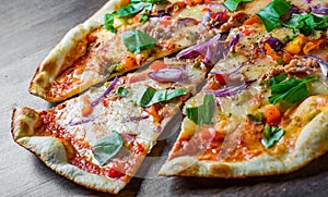 Pizza with Mozzarella cheese, onion, tuna fish, tomato sauce, pepper, basil. Italian pizza on wooden table