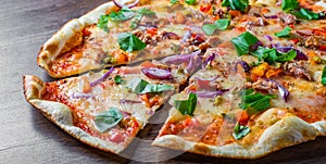 Pizza with Mozzarella cheese, onion, tuna fish, tomato sauce, pepper, basil. Italian pizza on wooden table