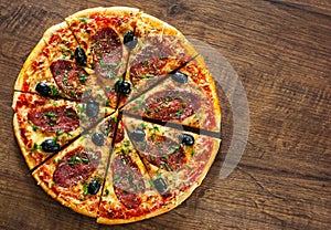 Pizza with Mozzarella cheese, salami, pepper, pepperoni, olives, Spices and Fresh Basil. Italian pizza on wooden background