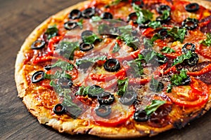 Pizza with Mozzarella cheese, salami, pepper, pepperoni, Tomatoes, olives, Spices and Fresh Basil. Italian pizza