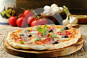 Pizza with mushrooms, olives and basil on wooden table photo