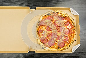 Pizza pepperoni in a cardboard take-away box.