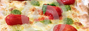 Pizza with pesto sauce and red peeled Tomatoes