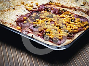 Pizza pie on a black baking tray