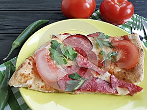 pizza piece with sausage fork knife ingredient on a black wooden