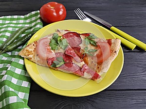 Pizza piece with sausage fork knife italian eat on a black woodeneatsalami