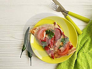 Pizza piece portion sausage fork eat pepper knife towel tomato on white wooden