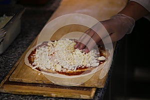 Pizza preperation. Adding cheese on pizza