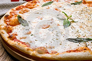 Pizza Quattro formaggi with mint on wooden table