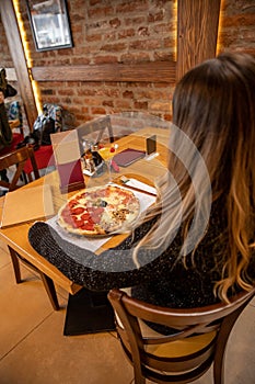 Pizza quattro stagioni with egg served in the restaurant. Woman sitting alone eating pizza in the restaurant photo