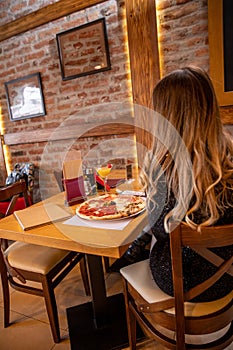 Pizza quattro stagioni with egg served in the restaurant. Woman sitting alone eating pizza in the restaurant