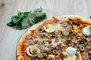 Pizza with red sauce, mozarella, ham, mushroom, boiled egg, green olives detail