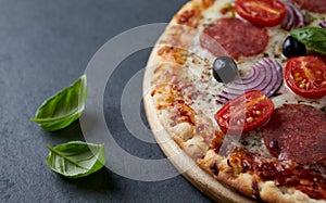 Pizza with salami, mozzarella cheese, cherry tomatoes, black olives, red onion and oregano