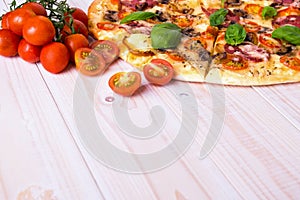 Pizza with Salami Vegetables and Spices on a white wooden background with copy space.