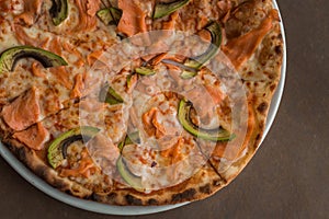 Pizza with salmon and avocado close-up