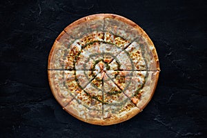 Pizza with salmon and cheese on a black stone background. Top view