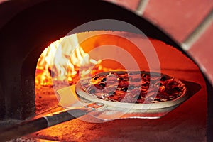 Pizza on the showel. Fire burning in the furnace. Close up view of wood in flames