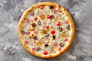 Pizza with smoked chicken, fried mushrooms, caramelized onions, tomatoes and cheese on gray surface