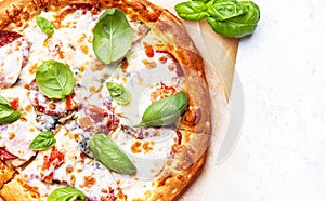 Pizza with spicy salami sausage, mozzarella cheese, tomato sauce and green basil, gray table background, top view close-up