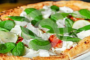 Pizza with spinach, zucchini slices, stracciatella cheese and tomatoes. Italian cuisine