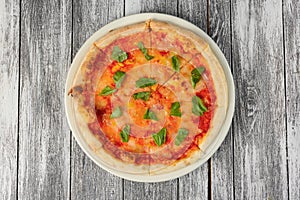 Pizza with tomato sauce and basil on wooden background. Top view, close-up