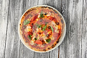 Pizza with tomatoes, cheese and basil on wooden background. Closeup, top view