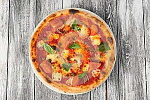 Pizza with tomatoes, cheese and basil on wooden background. Closeup, top view