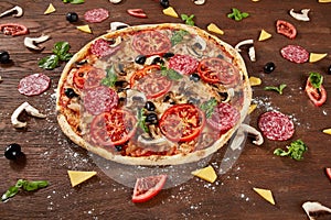 Pizza with tomatoes, mozzarella cheese, black olives and basil. Delicious italian pizza on wooden pizza board.