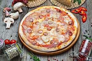Pizza with tomatoes, mozzarella cheese, black olives and basil. Delicious italian pizza on wooden pizza board.