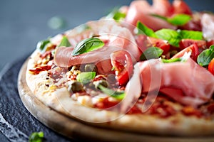 Pizza topped with black forest ham, capers and tomatoes