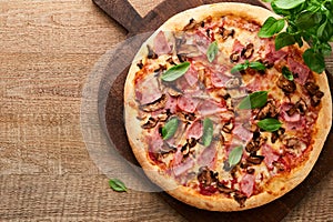 Pizza. Traditional Bacon pizza with ham, mushrooms, pickled cucumber and cheese and cooking ingredients tomatoes basil on wooden