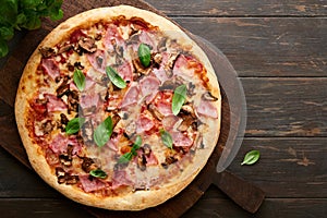 Pizza. Traditional Bacon pizza with ham, mushrooms, pickled cucumber and cheese and cooking ingredients tomatoes basil on wooden