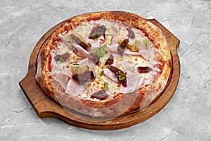 pizza with veal, ham, cheese and sun-dried tomatoes on a gray table