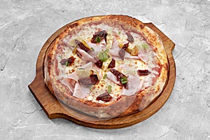 pizza with veal, ham, cheese and sun-dried tomatoes on a gray table