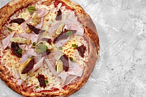 pizza with veal, ham, cheese and sun-dried tomatoes on a gray table