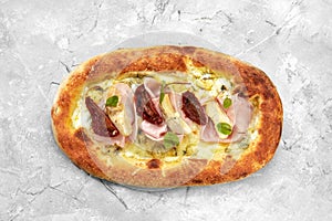 pizza with veal, ham, cheese and sun-dried tomatoes on a gray table