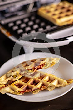 Pizza waffles, piffle. Waffles stuffed with sausage, cheese, tomatoes on a plate