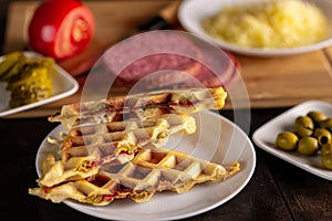 Pizza waffles, piffle. Waffles stuffed with sausage, cheese, tomatoes on a plate surrounded by cooking ingredients