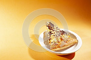 Pizza on white ceramic plate, with cheese and chocolate sprinkles, on orange lighting background