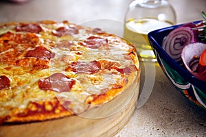 Pizza on wood platter with salad and olive pil