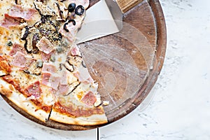 Pizza on wooden plate on table