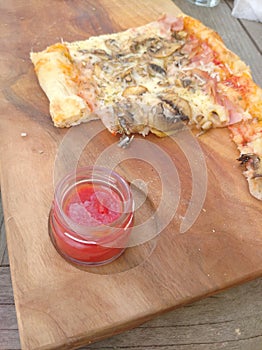 Pizza on wooden table with tomato sauce