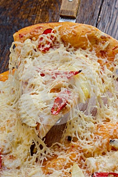 Pizza on a wooden table at which raise the class with stringy cheese