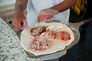 Pizzaiolo puts a four season pizza on the peel, ready to bake.