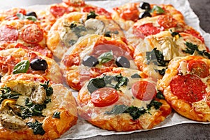 Pizzette Italian mini pizzas or pizza bites close-up on parchment. Horizontal photo
