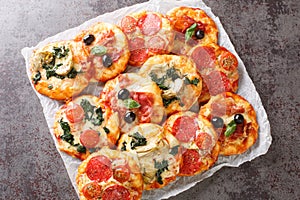 Pizzette Italian mini pizzas or pizza bites close-up on parchment. Horizontal top view photo